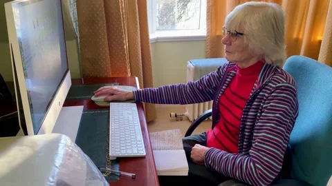 Senior elderly lady using a computer to send emails Stock Footage 228876359