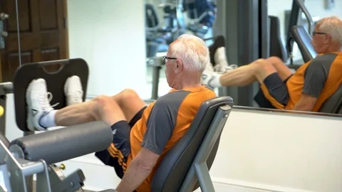 Senior elderly man exercising in the gym doing leg press Stock Footage