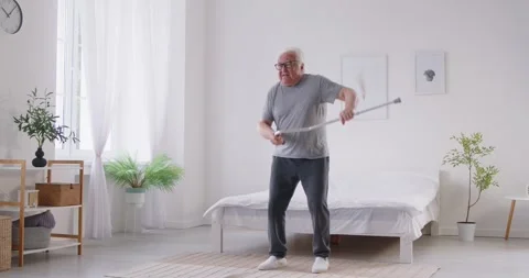 Senior elderly man getting out of bed and starting dancing holding crutch in 動画素材 311288647