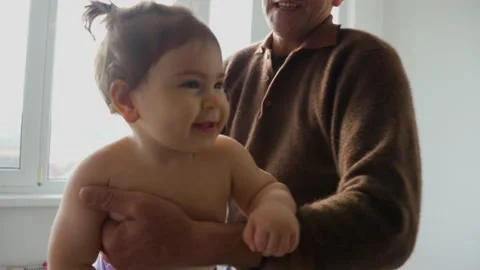 Senior elderly man playing to his baby granddaughter, holding him in the air Stock Footage 178140174