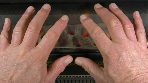 Senior / elderly / old man’s hands warming in front of a gas fire. Video stock 143098372