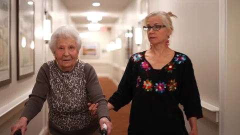 Senior elderly old mother using a walker and daughter in law walking to elevator Stock Footage 267857621