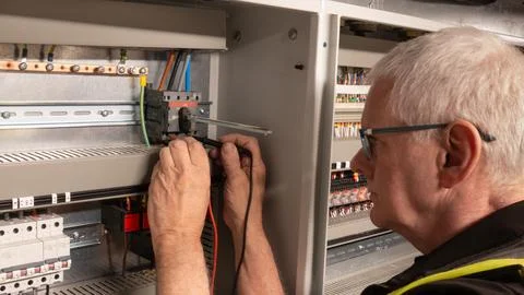 Senior electrical engineer using a multi meter to test a power switch Stock Photos