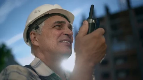 Senior engineer builder using a walkie talkie at a construction site Stock Footage 91878184