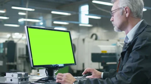 Senior engineer in glasses is working on a desktop computer with a green screen Stock Footage
