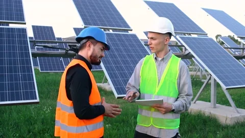 A senior engineer with a solar panel installation plan explains to a worker how Stock Footage 140002260