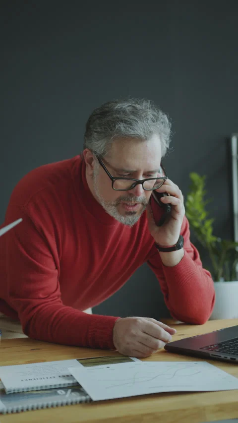 Senior Engineer Using Laptop and Talking on Mobile Phone in Office Stock Footage 270572360