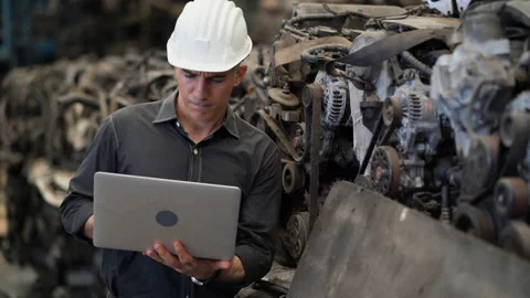 Senior engineer using laptop computer checking list old used car engine in ma Stock Footage 153568204