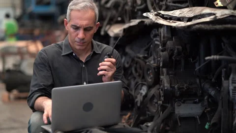 Senior engineer using laptop computer and walkie talkie checking old used car Video stock 153568220