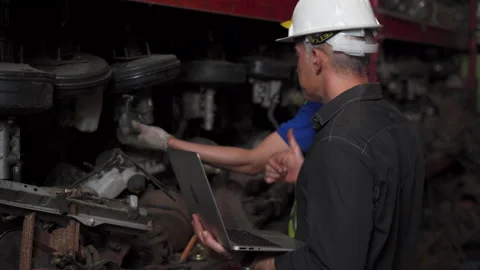 Senior engineer using laptop computer checking list old used car engine  with Stock Footage 153569663