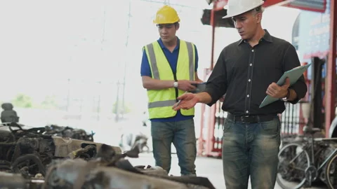 Senior engineer using laptop computer checking list old used car engine with Stock Footage 153570063