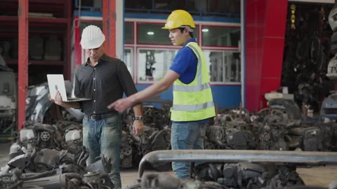 Senior engineer using laptop computer checking list old used car engine with Stock Footage 153571046