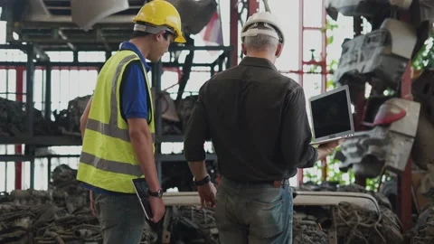 Senior engineer using laptop computer checking list old used car engine with Stock Footage 153571061