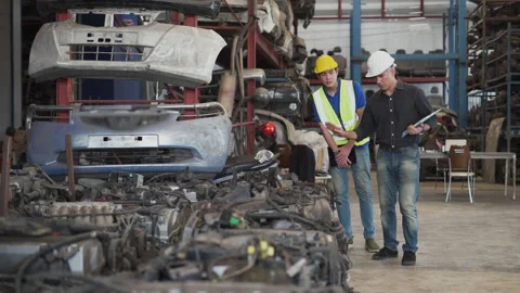 Senior engineer using laptop computer checking list old used car engine with Stock Footage 153571183