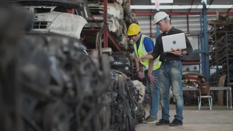 Senior engineer using laptop computer checking list old used car engine with Stock-Footage 153571488