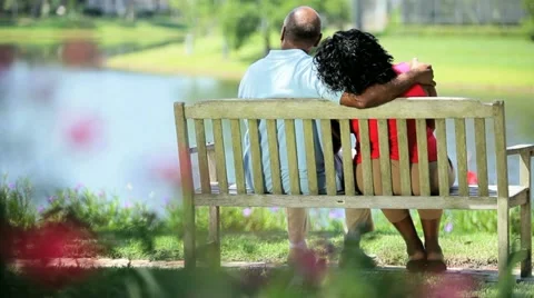 Senior ethnic couple sitting bench enjoying lake view Stock Footage