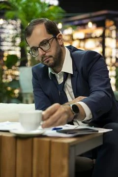 Senior executive drinking coffee cup after hours working beside reports Stock Photos