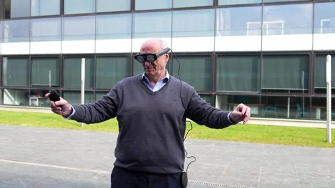 Senior Executive Interacting with Virtual Reality Glasses and Controller Stock Footage 275860939