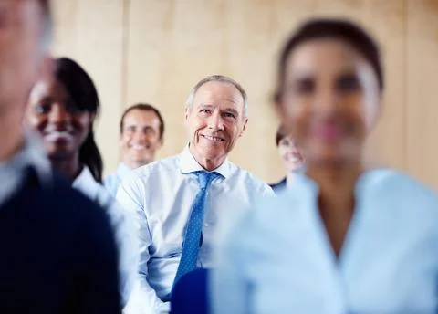Senior executive sitting with group. Focus on senior Business man surrounded by Stock Photos
