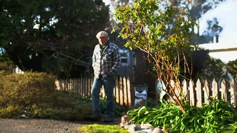 A senior farmer walks through the front gate of his home. Stock-Footage 88373896