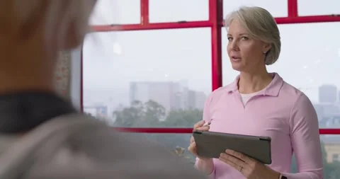Senior female coach tapping tablet with stylus as client entering, coaching in Video stock 342031928