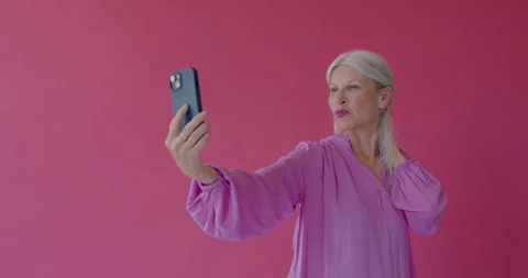 Senior female Posing and Taking Selfie with Phone in Pink Studio Stock Footage 250198286