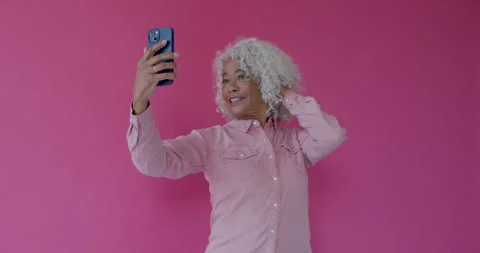 Senior female Posing and Taking Selfie with Phone in Pink Studio Stock Footage 250198488