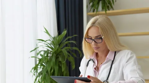 Senior female therapist using online healthcare app on digital computer tablet Stock Footage