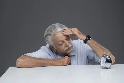 Senior Finance Manager Hand On His Head And Is Looking At An Alarm Clock.  스톡 사진