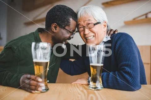 Senior friends drinking beer and having fun in bar Stock Photos