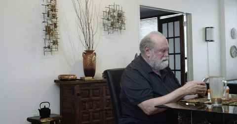Senior Gay Man Using Smart Phone as Husband Walks in and Kisses Him Stock Footage 111497433
