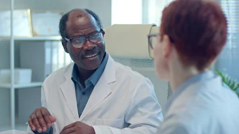 Senior General Practitioner Talking to Colleague at Meeting in Medical Office Stock Footage 265640517