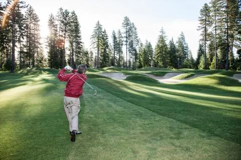 Senior golfer hitting a second shot from the fairway of a golf course. Stock Photos