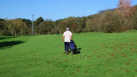 Senior golfer, seen from behind, walking across course with golf cart towar.. Stock Footage 292017186