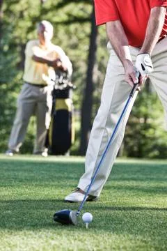 Senior golfers teeing off on a golf course hole. Stock Photos