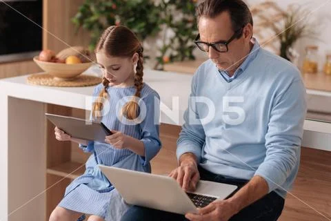 Senior grandfather and young girl surfing Internet at home Stock Photos