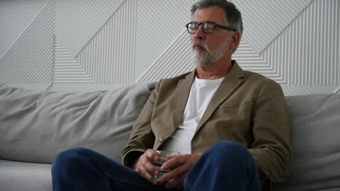 Senior gray haired bearded man drinks water from a glass Stock Footage 278986889