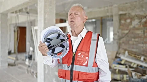 Senior grey-haired man architect using hardhat as a hand fan at constructio.. 스톡 동영상 242914769