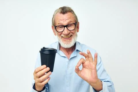 Senior grey-haired man with a black glass in his hands a drink isolated Stock Photos