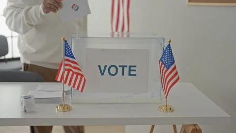 Senior grey haired man drops ballot with hand into clear ballot box at a po.. Stock Footage 337377014