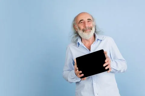 Senior grey-haired man with tablet, device isolated over light background. Stock Photos