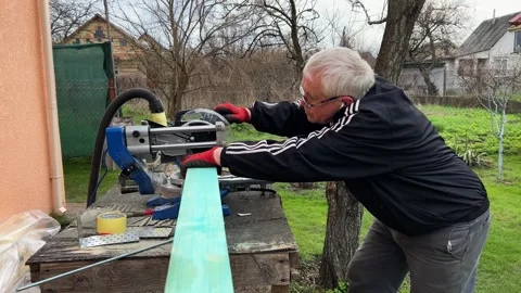 Senior grey-haired white man operates miter saw woodworking with square wooden Vídeo Stock 243825146