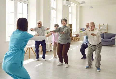 Senior group doing squat exercise with physiotherapist in gym Fotos de archivo