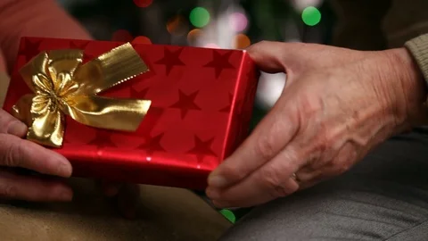 Senior hands giving and receiving xmas present in front of christmas lights Stock-Footage 87900611