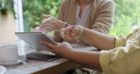 Senior hands holding tablet during cafe meeting while another pair of hands Stock Footage 309320932