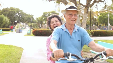 Senior Hispanic Couple Riding Bikes In Park Stock Footage