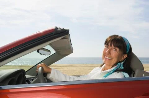 Senior Hispanic woman driving convertible car Stock Photos