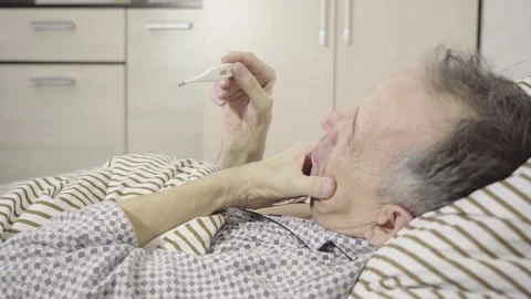 Senior holding a thermometer lying in bed Stock Footage 155068523