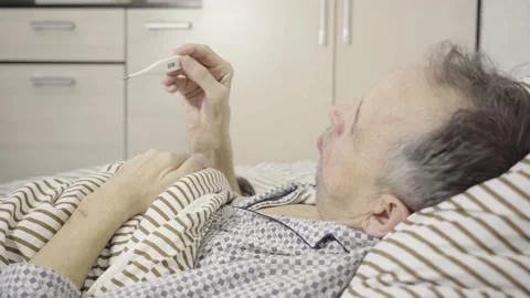 Senior holding a thermometer lying in bed Video stock 163119787