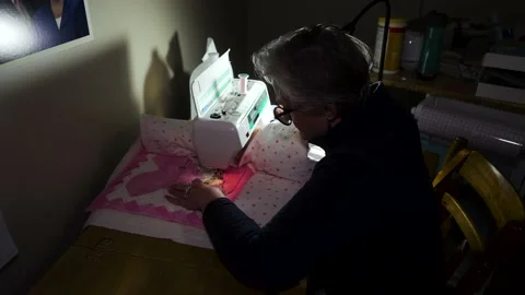 Senior homemaker using a sewing machine to stitch heart patterns with a Stock Footage 168421159